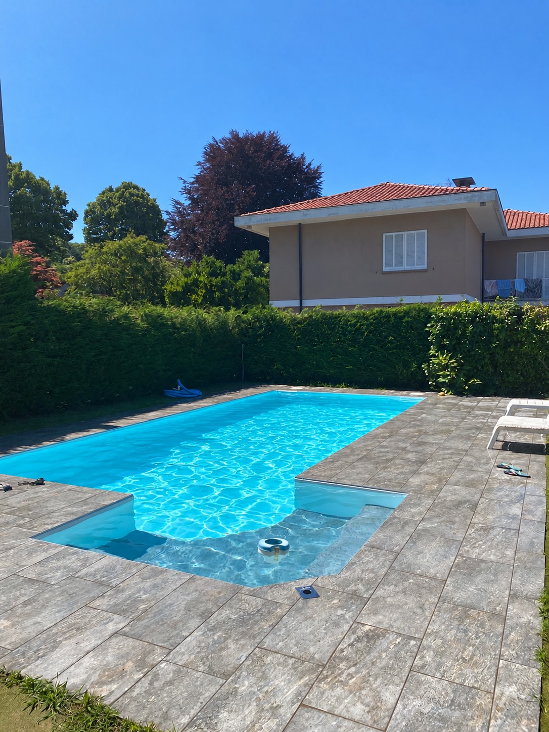 Piscina completata con acqua azzurra e pavimentazione esterna; persone e gonfiabili rimossi dalla fotografia